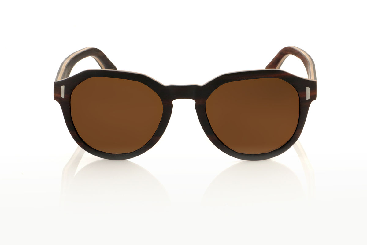 Wood eyewear of Ebony IZARO. IZARO wooden sunglasses are an expression of style and craftsmanship, made entirely of laminated ebony wood both outside and inside, with an intermediate layer of maple wood that provides a clear and striking contrast. The distinctive black and brown grain of the ebony is perfectly complemented by the distinctive hexagonal shape on the brow, while the silver metallic inlays on the sides add a touch of elegance and sophistication. With measurements of 145x50 and a caliber of 51, the IZARO are presented as a perfect option for those looking to stand out with a unique accessory that combines the natural beauty of wood with an innovative design. for Wholesale & Retail | Root Sunglasses® 